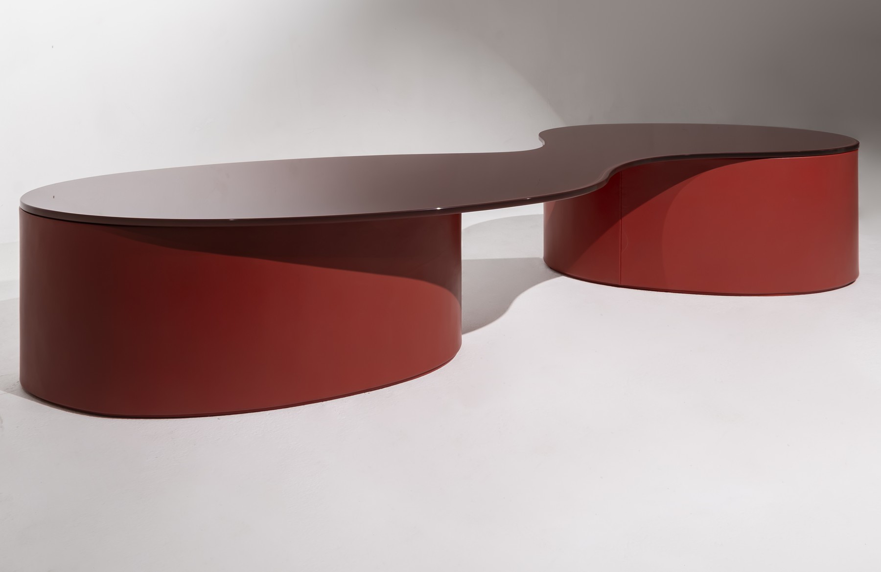 Isolated view of the red NEXUM coffee table's flowing top and paired bases