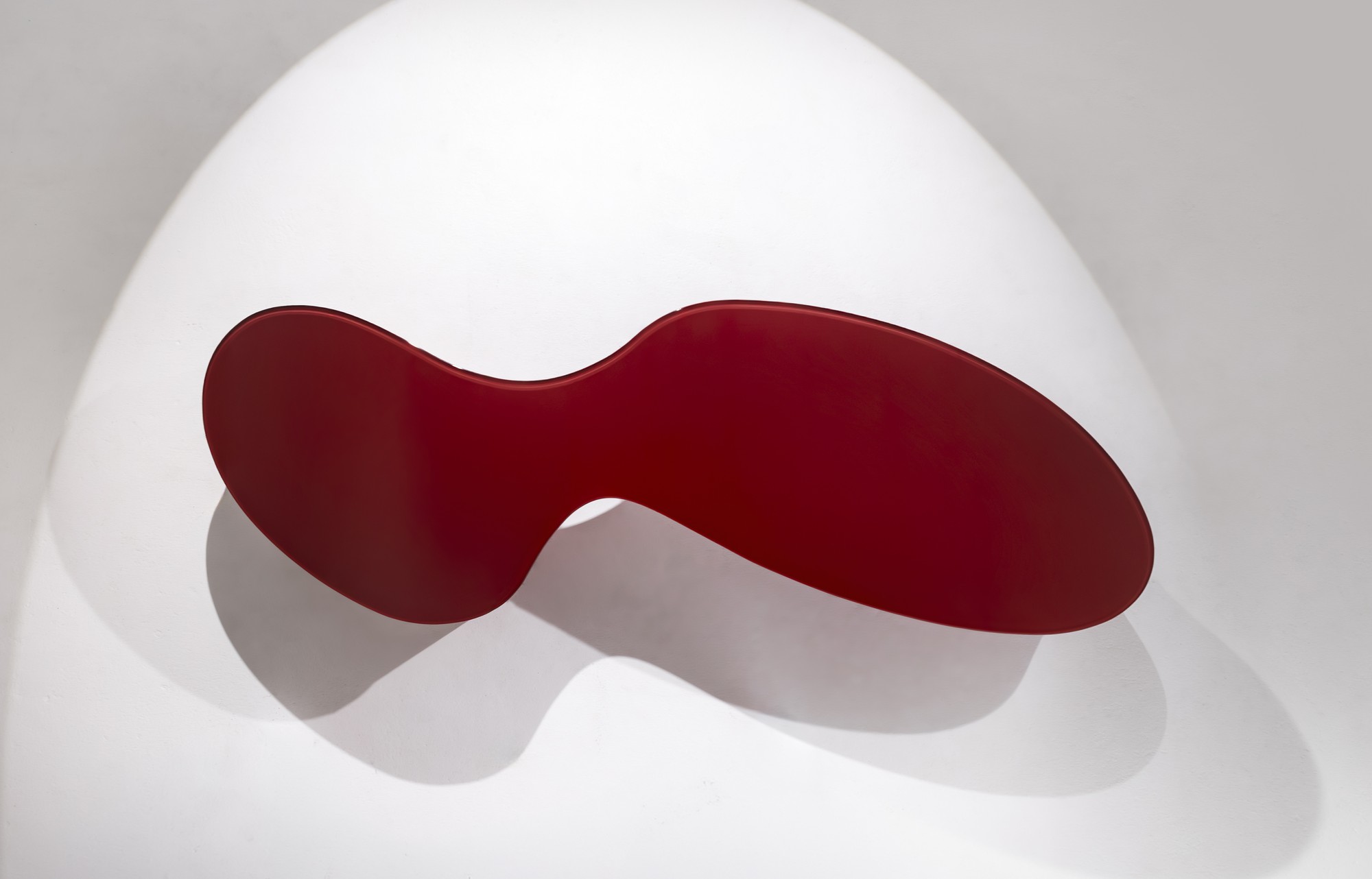 Overhead view of the red NEXUM coffee table and its sculptural shadow
